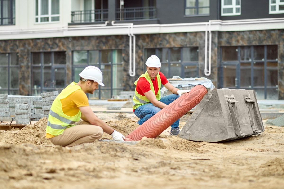 Construction crew installing new pipe in a trench, illustrating trenchless pipe lining repair lifespan factors
