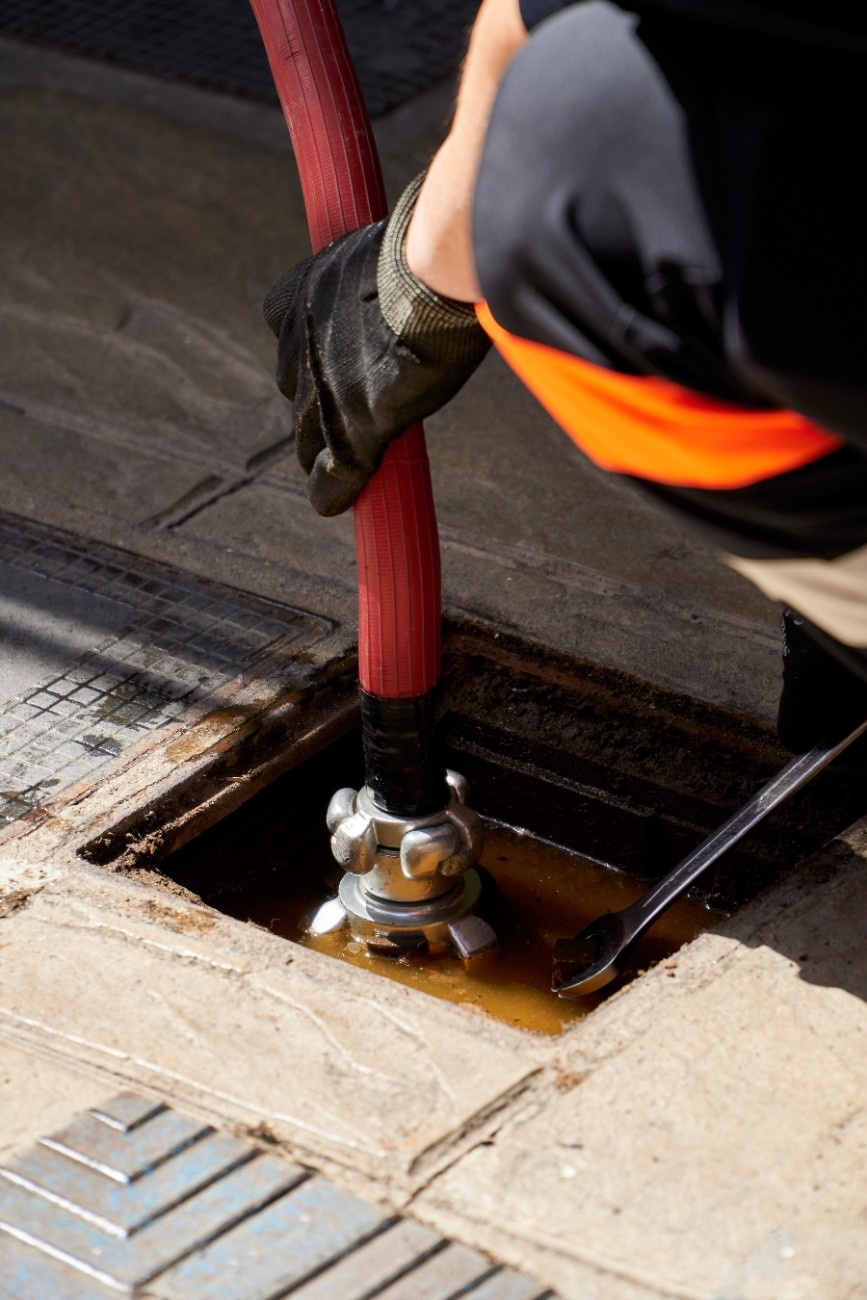 Sewer maintenance crew pumping industrial liquid through a red hose during a Seattle service call