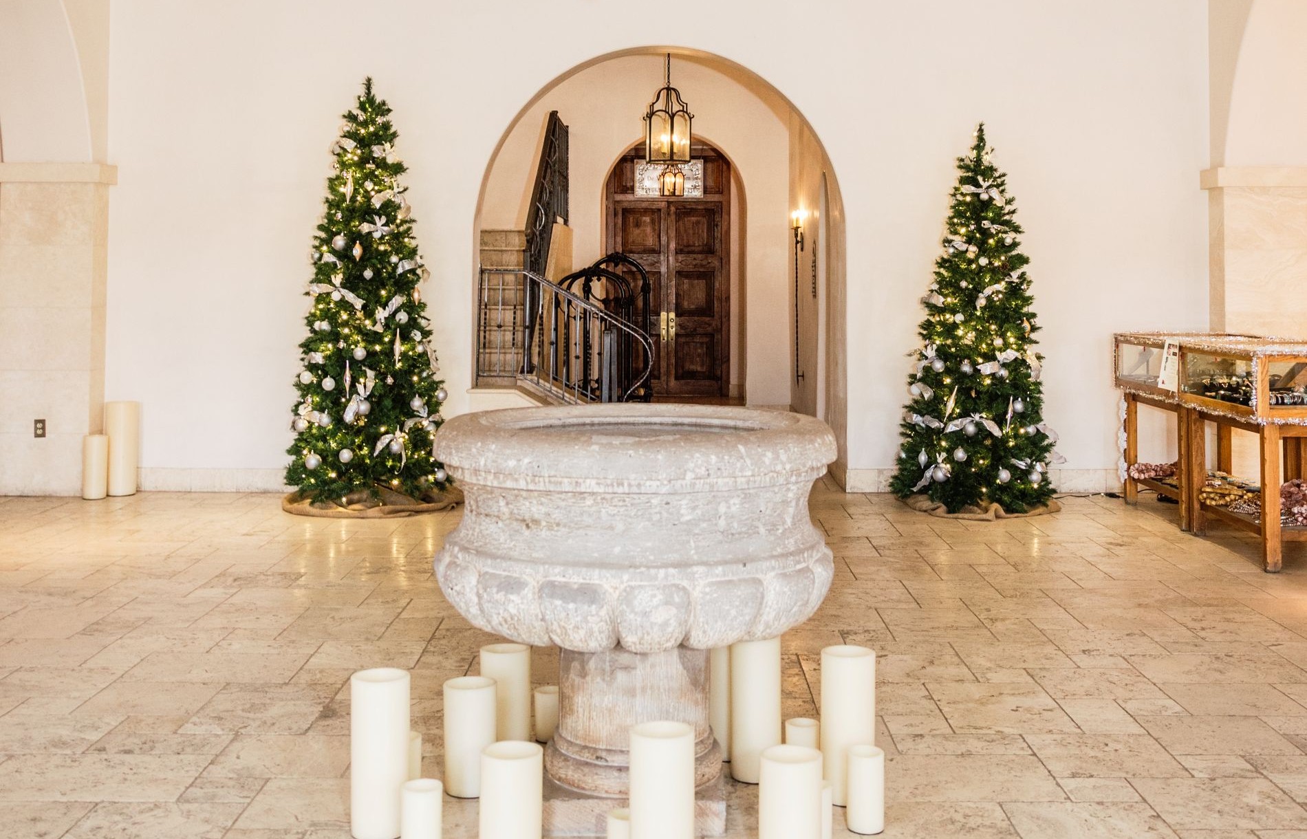 Lobby of St. Francis with candle throughout and two Christmas trees