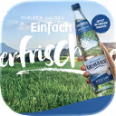 Flasche Gerolsteiner Mineralwasser vor grünem Gras unter blauem Himmel mit weißem Text ‚Einfach erfrischend‘.