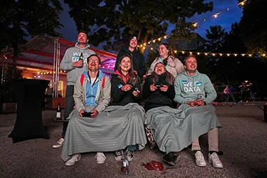 btelligent Team beim Sommerfest am Abend mit Decken und Getränken unter Lichterketten