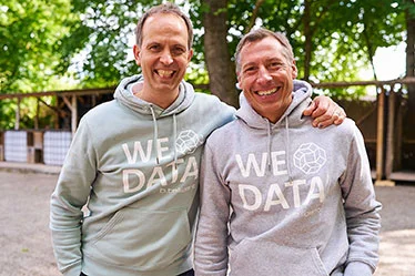 lächelnde btelligent Geschäftsführer im „WE LOVE DATA“-Hoodie bei einem Team-Event