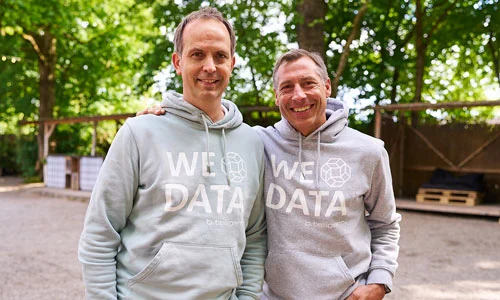 lächelnde btelligent Geschäftsführer im „WE LOVE DATA“-Hoodie bei einem Team-Event