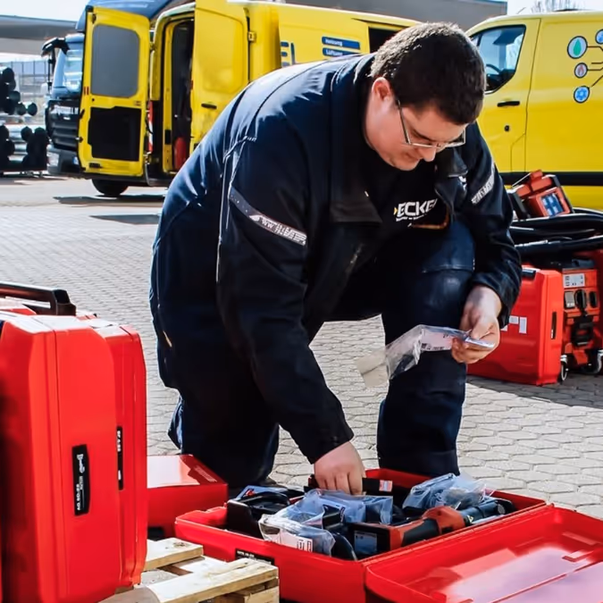Eckel Mitarbeiter über geöffneten Werkzeugkoffer gebeugt.