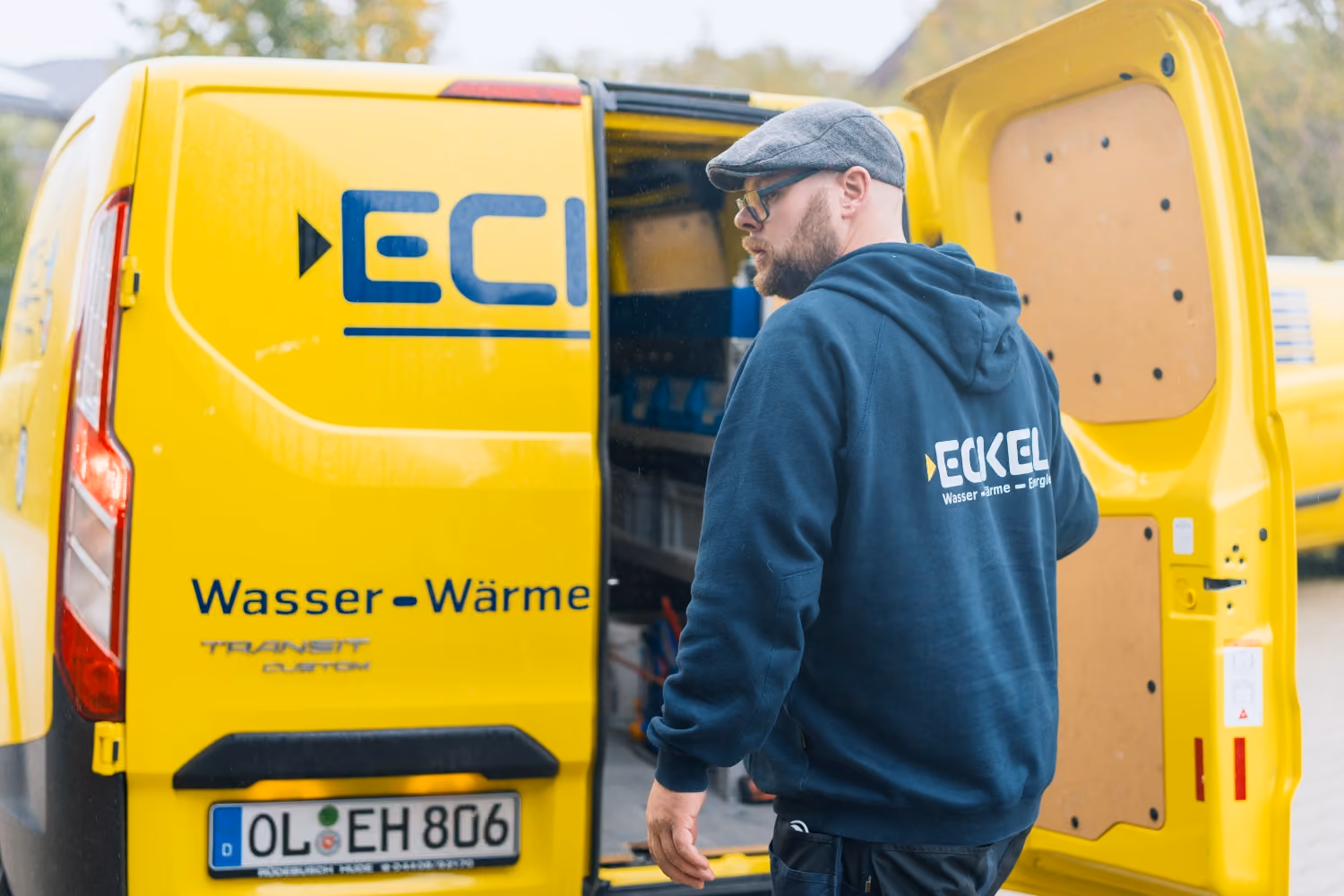 Eckel Handwerker am Firmenwagen mit dem Rücken zur Kamera