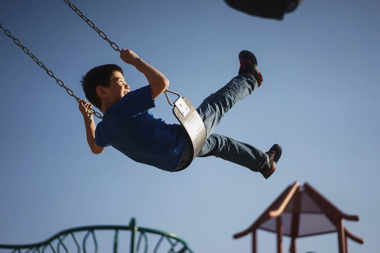 A happy Asian boy playing on a swing.