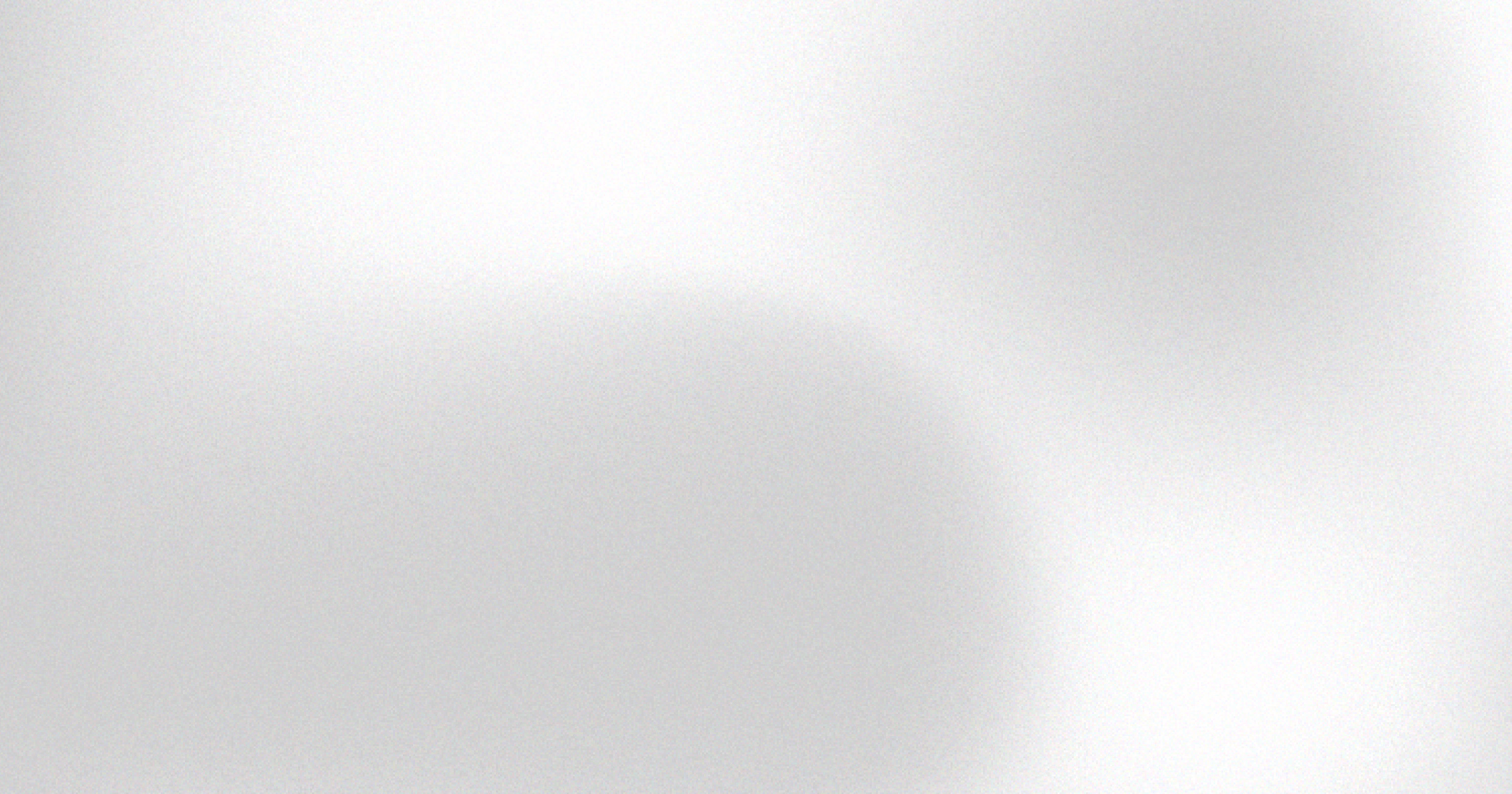 Blurry black and white abstract image with dark circular and oval shapes on a light background.