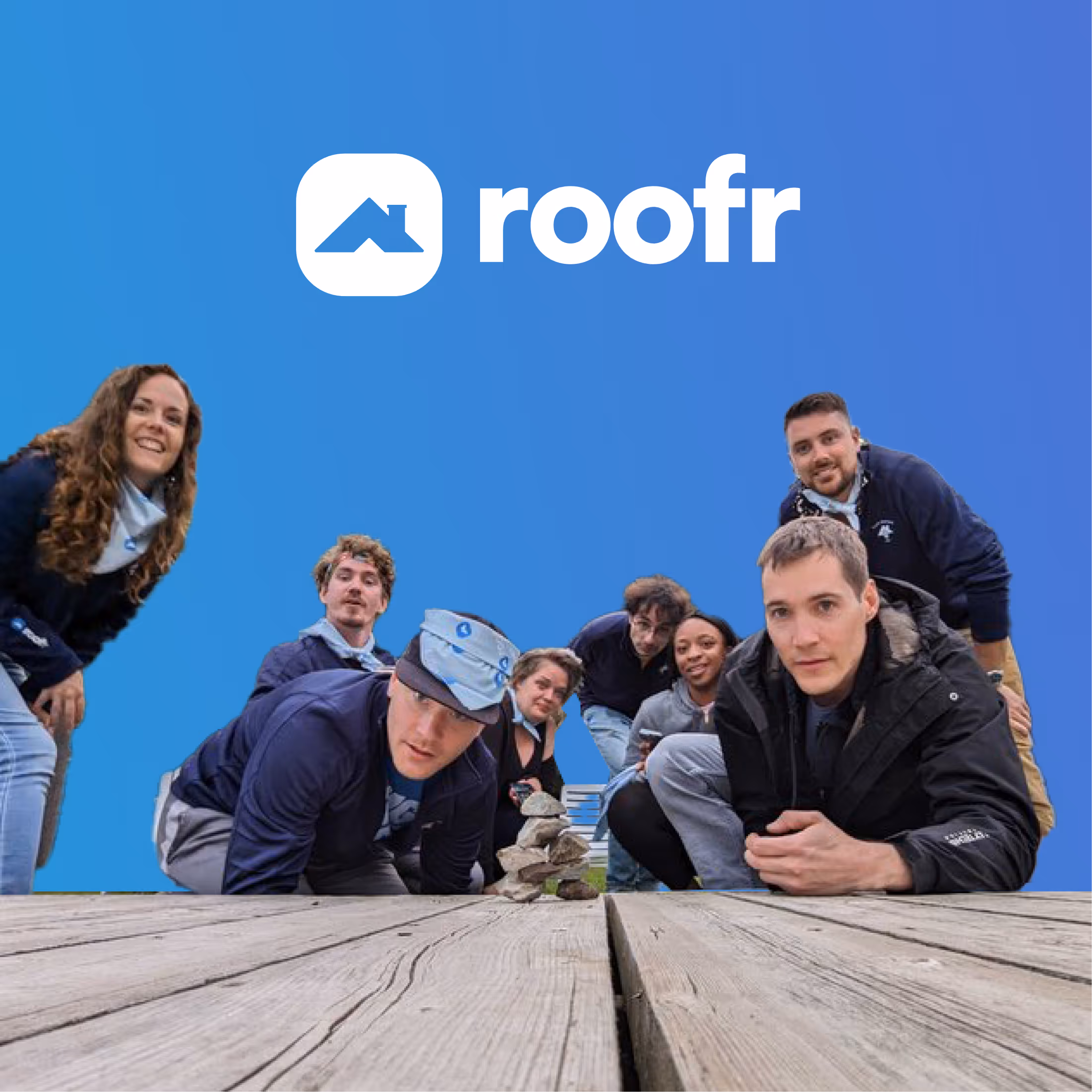 Group of seven people leaning towards the camera on a wooden surface with the roofr logo and a blue background above them.