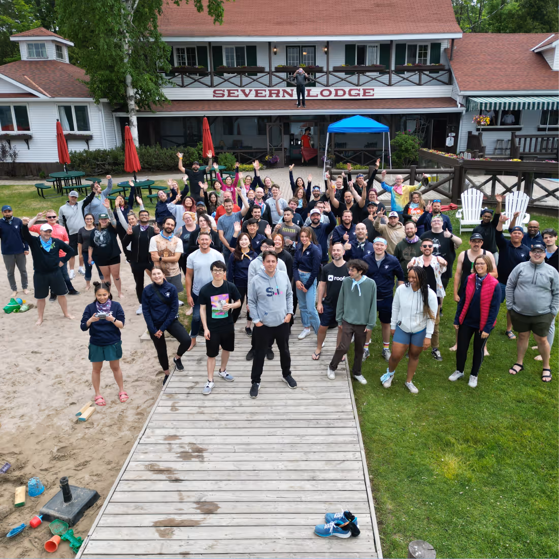 Large group of people smiling and waving on a dock in front of a building with the sign 'SEVERN LODGE'.