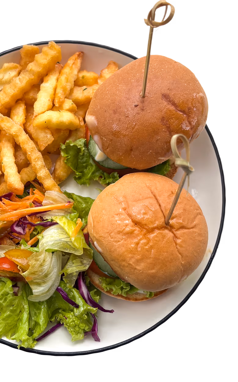Plate with two mini sandwiches with lettuce and cucumber, crinkle-cut fries, and mixed vegetable salad.
