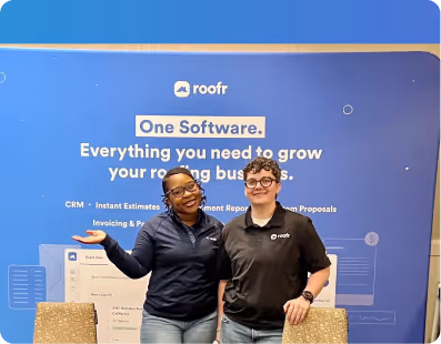 Two smiling people standing in front of a blue Roofr banner about software for roofing businesses.