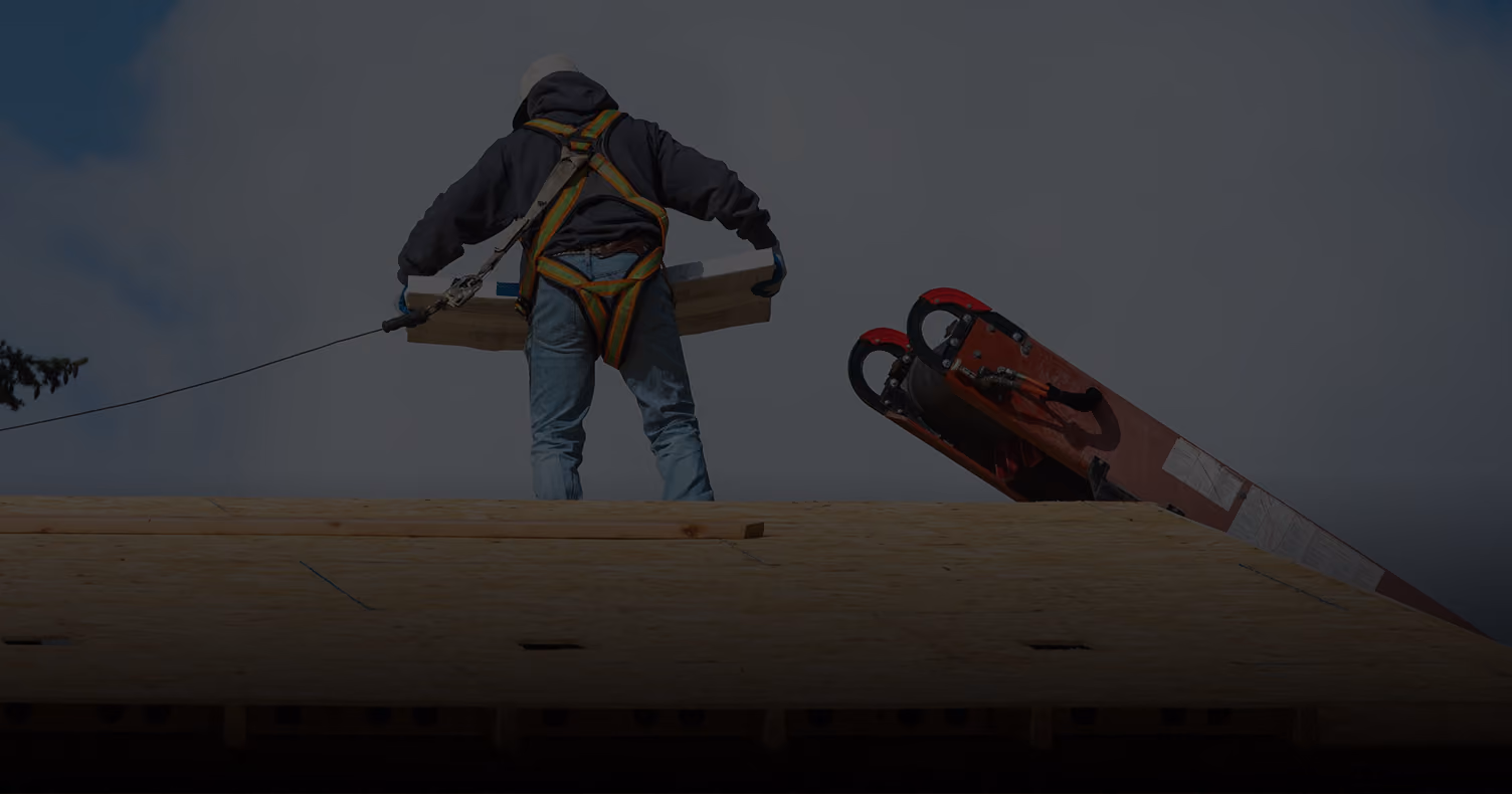 Three workers installing roofing felt on a house roof with trees in the background.