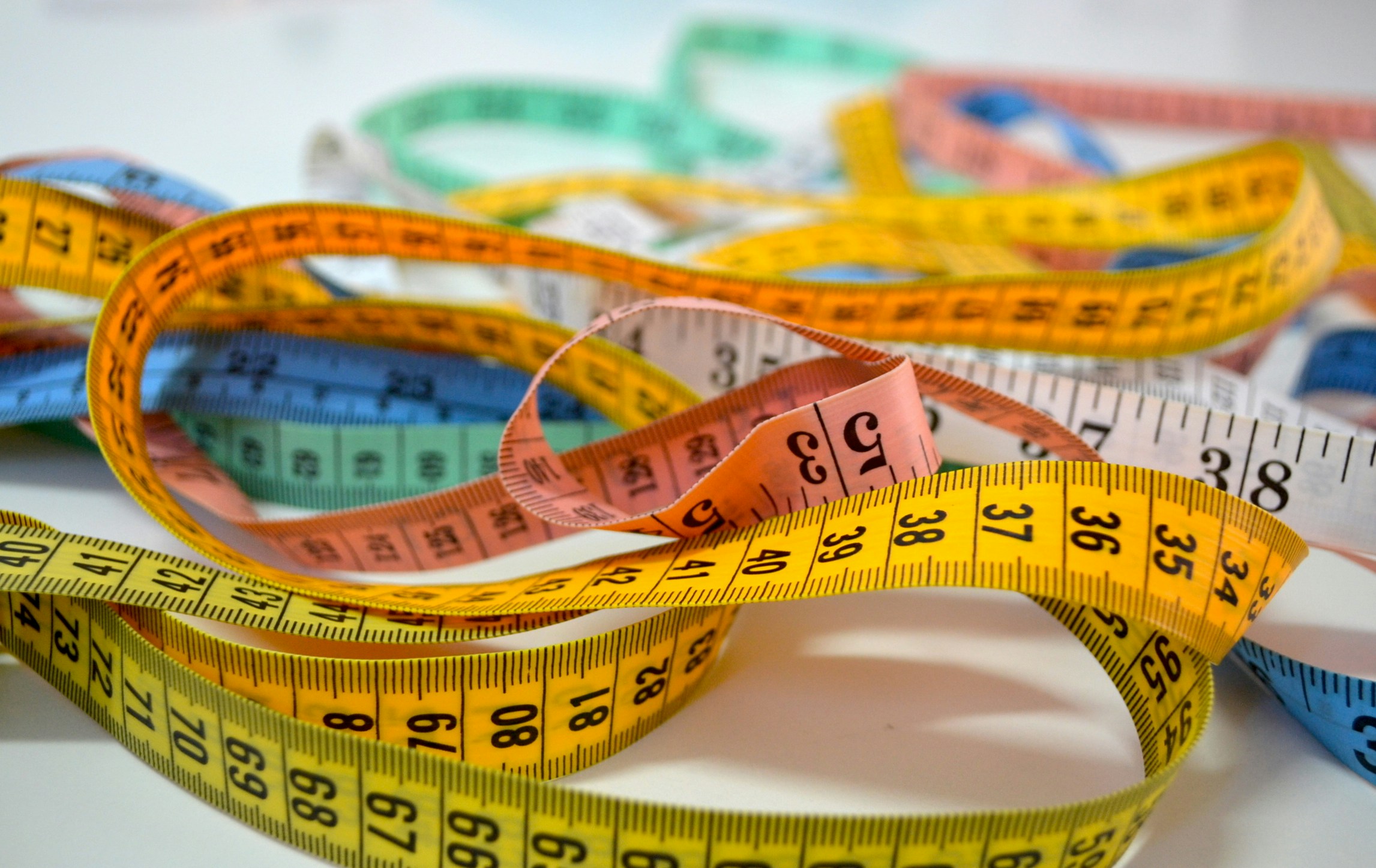 A pile of measuring tape of all different colors, representing the old-school way of measuring complicated roofs manually. Photo credit to Patricia Serna via Unsplash.