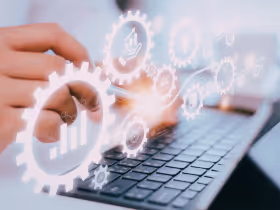 Hands typing on a keyboard with gear images overlaid above, representing AI-powered workflow automation.