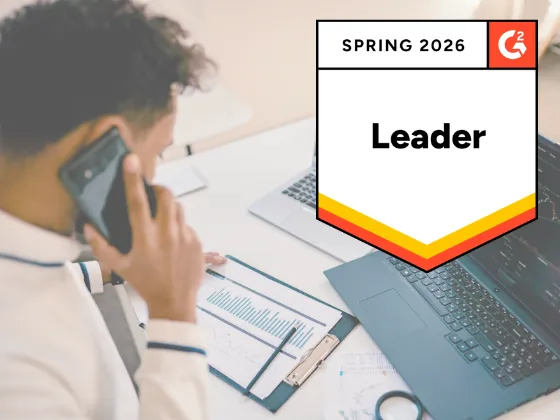 A photo of a roofing company team member at a desk using a CRM -- next to Roofr's Spring 2026 Leader G2 badge.