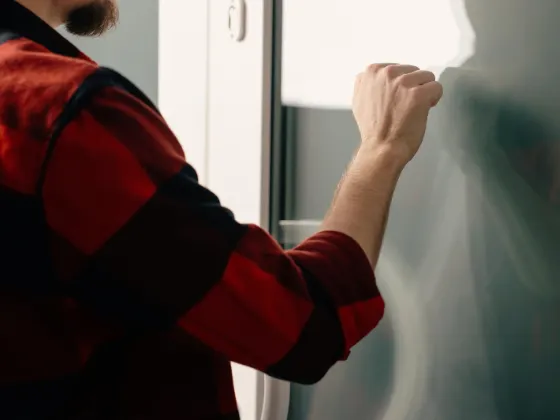 A photo of a roofer knocking on a door, doing door to door roofing sales.