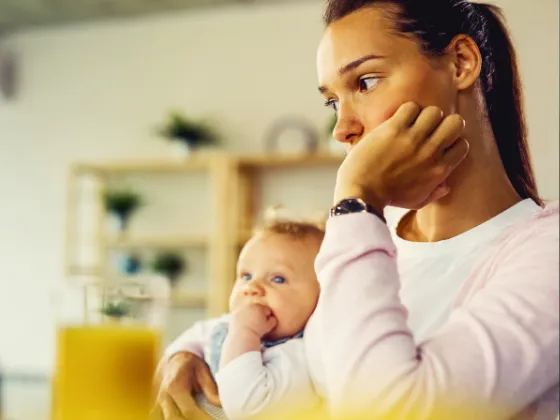 A woman and her baby sitting in their home, representing how homeowners choose a roofer and what their primary concerns and motivations are.