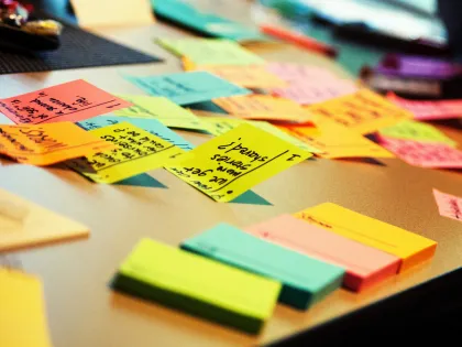 A photo of colorful sticky notes on a desk, representing an outdated method of roofing project management without a dedicated CRM.