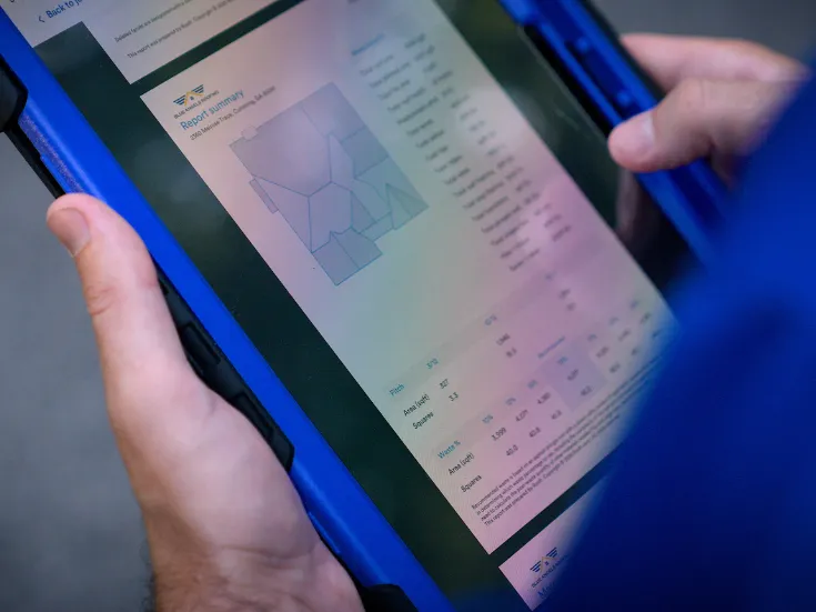 Roofer looking at a Roofr Measurement report on a tablet