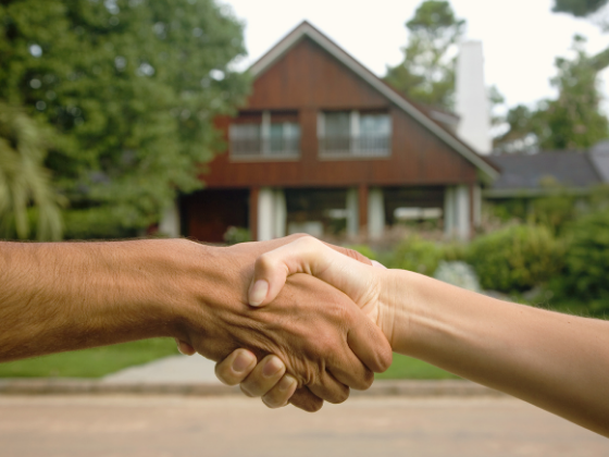 A roofer shaking hands with a happy homeowner post-install.
