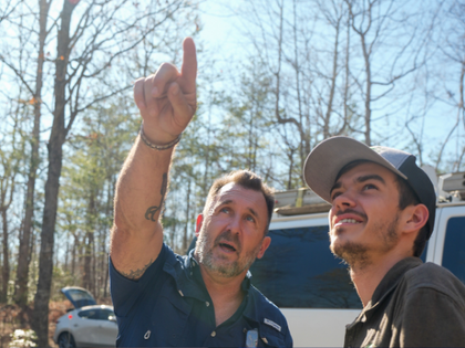 Roofer pointing to a roof with a crew member standing next to him