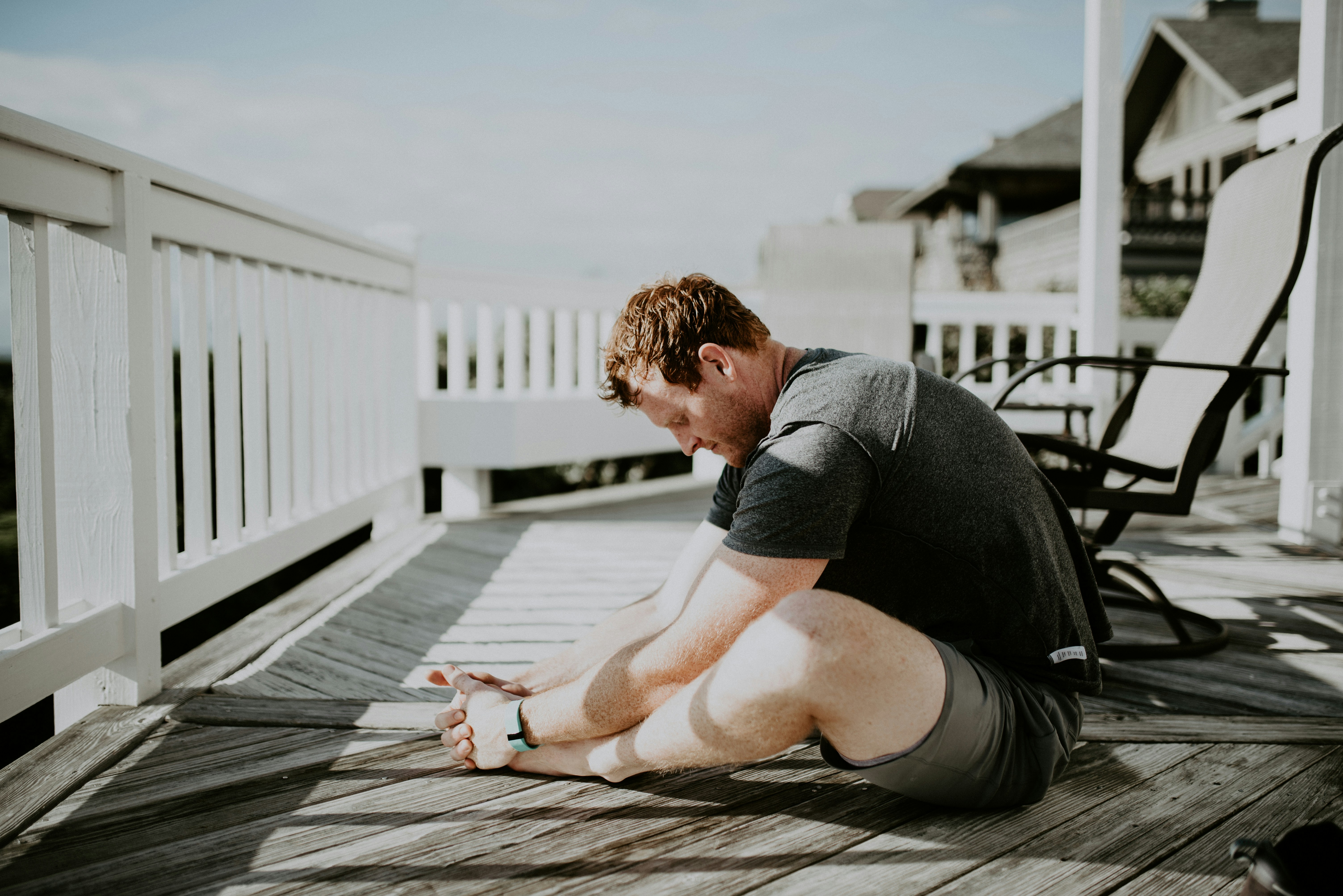 Man on back deck stretching before work in a butterfly stretch.