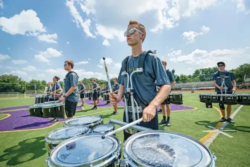 A group of young men playing marching drums on a field.