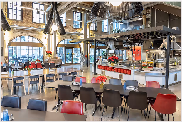 Modern corporate cafeteria with open kitchen and dining area.