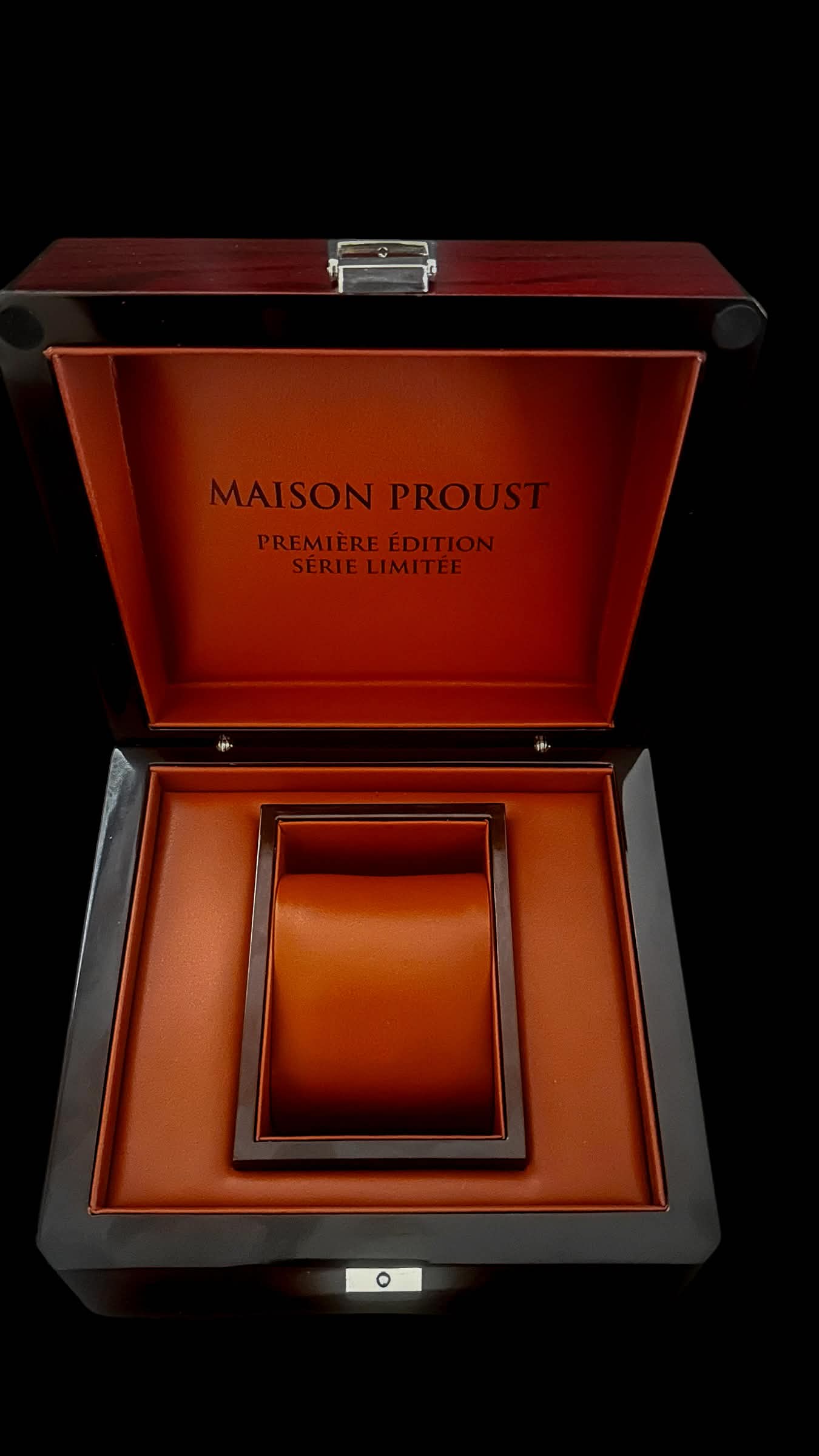Boîte de montre de luxe en bois foncé avec intérieur en cuir orange marqué Maison Proust Première Édition Série Limitée, avec coussin pour montre.
