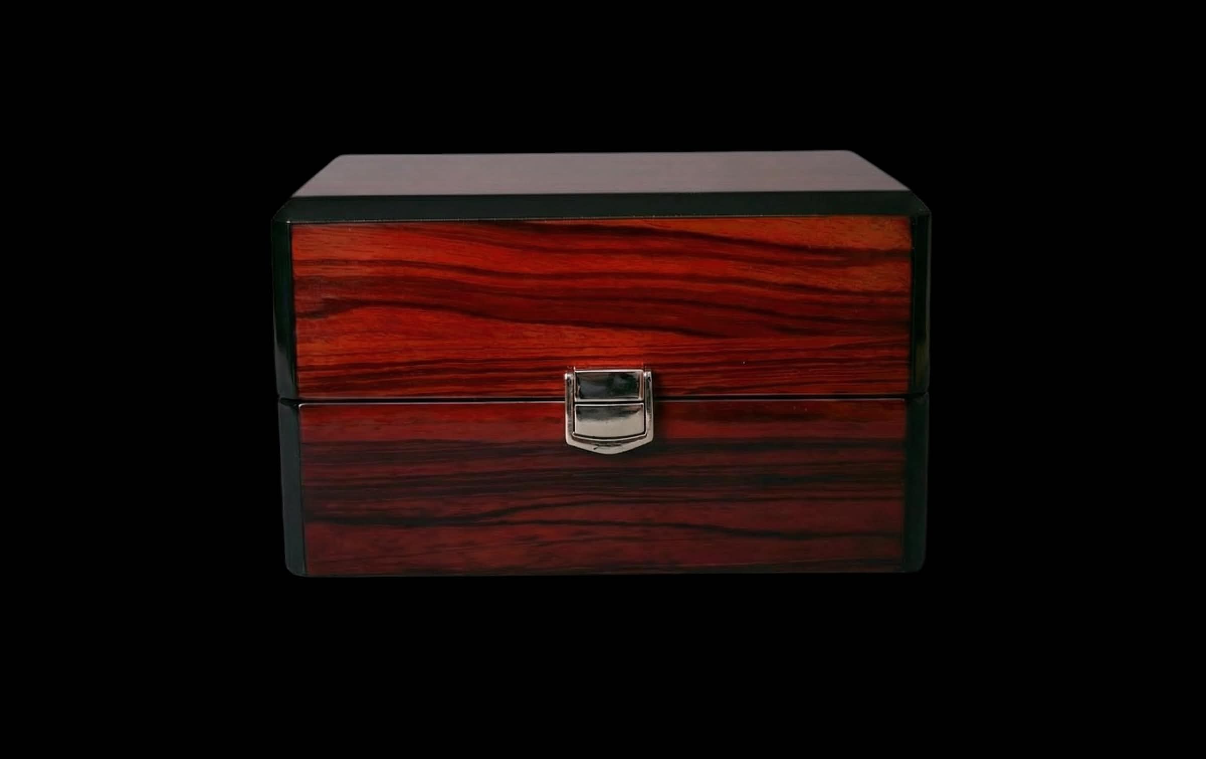 Boîte en bois verni avec motif de grains rouges et poignée métallique au centre.
