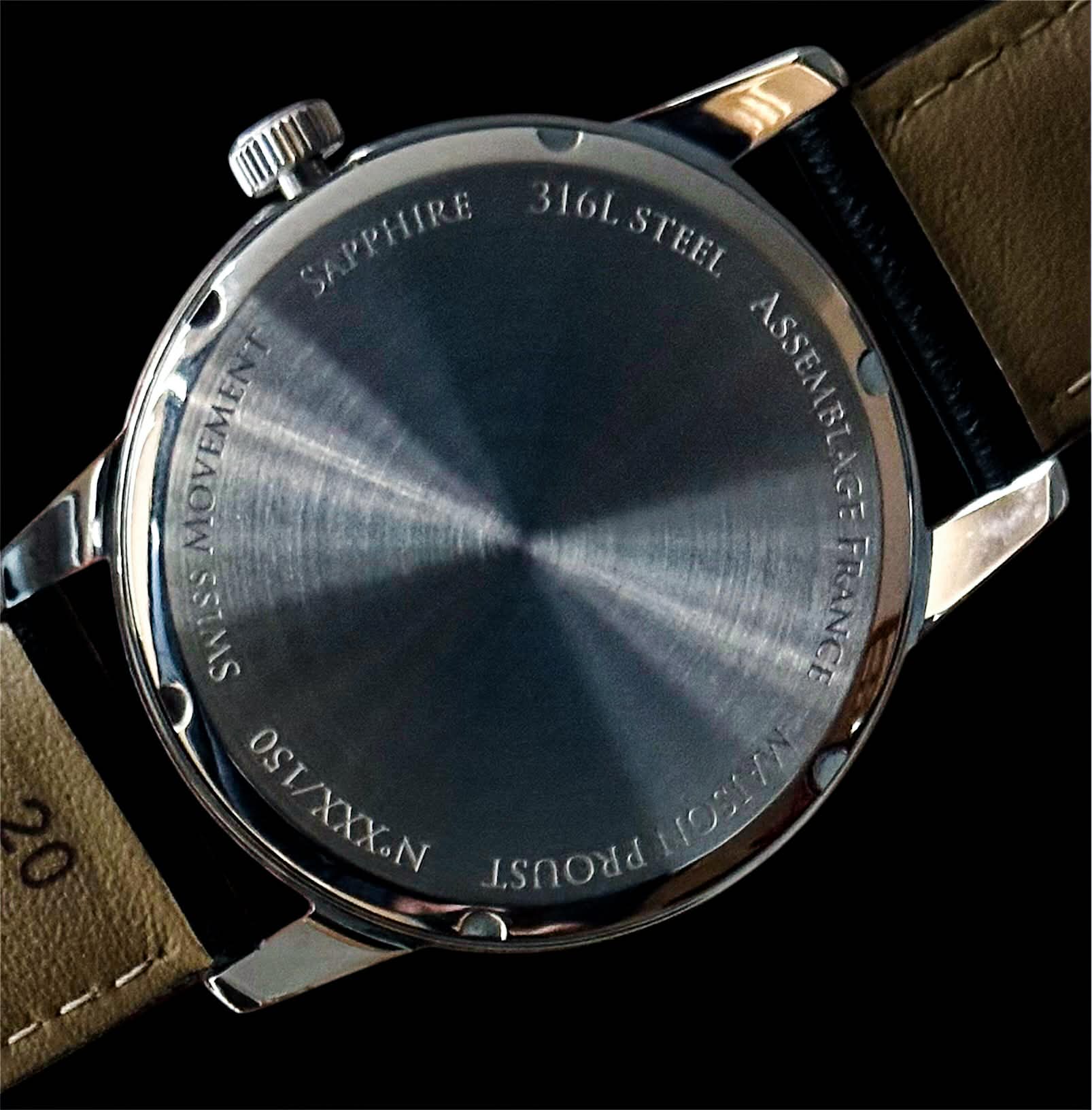 Dos d'une montre en acier inoxydable poli avec gravure indiquant mouvement suisse, verre saphir, acier 316L et assemblage en France.
