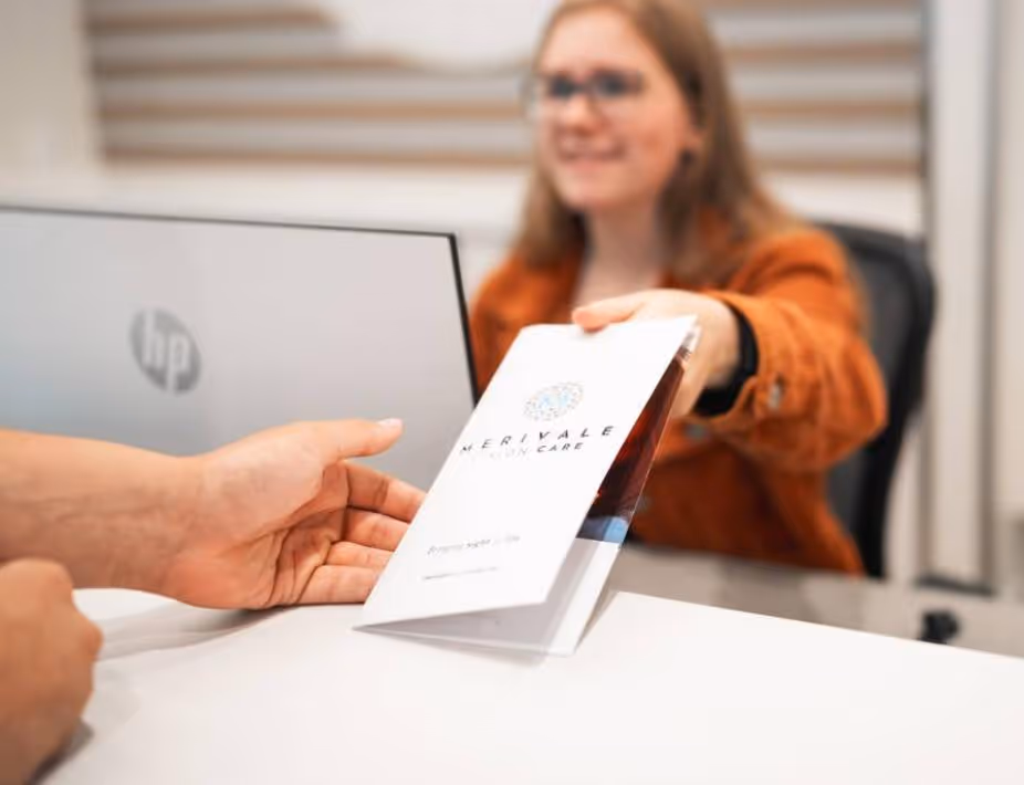 Front desk receptionist handing client a Merivale Vision Care brochure