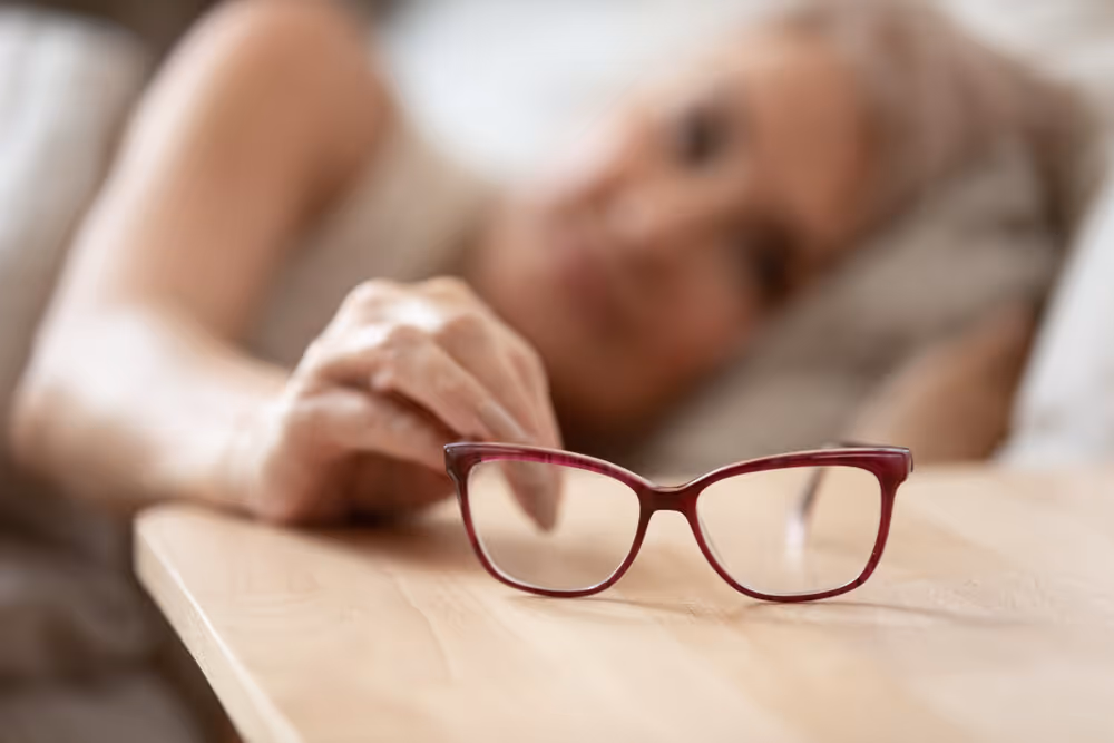 Vision Loss. Lady reaching for glasses. Blurred image.