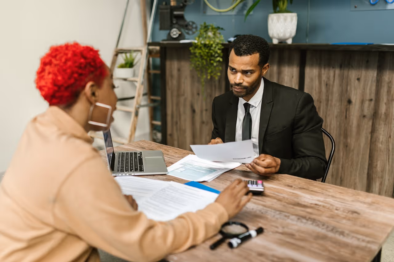 man in black suit sitting in front of woman in brown blazer