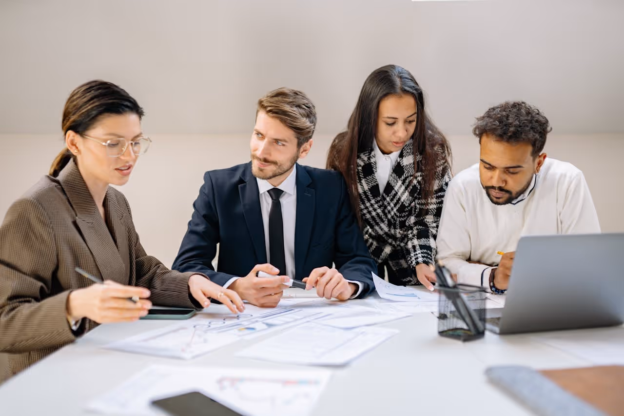 men and women sitting at table with documents