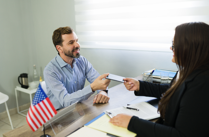 man and woman discussing business visas in an office, american flag visible