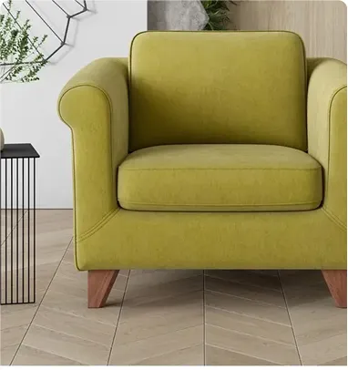 A chartreuse green upholstered armchair with wooden legs on a herringbone patterned floor.