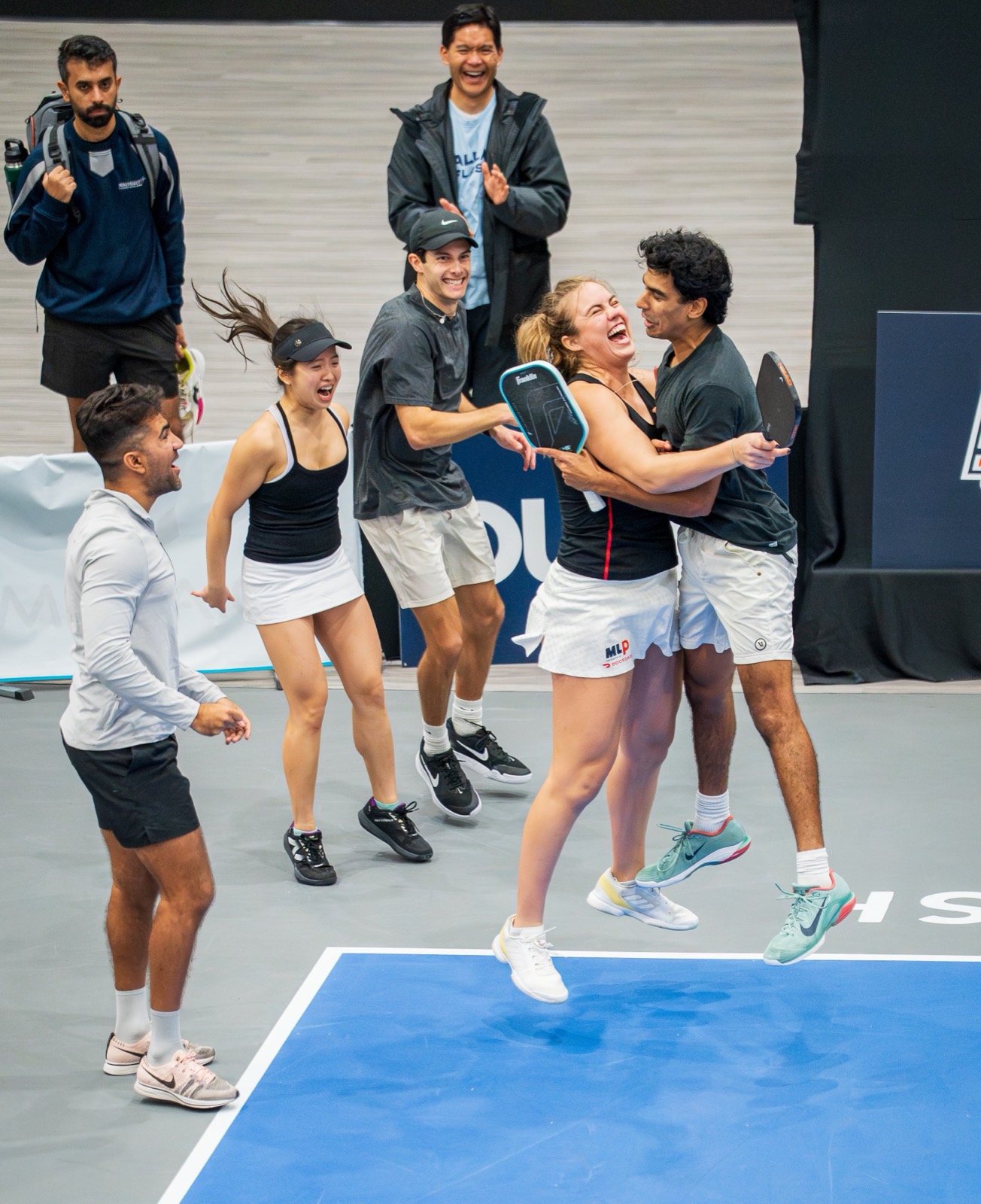 College pickleball players celebrating a match win on court