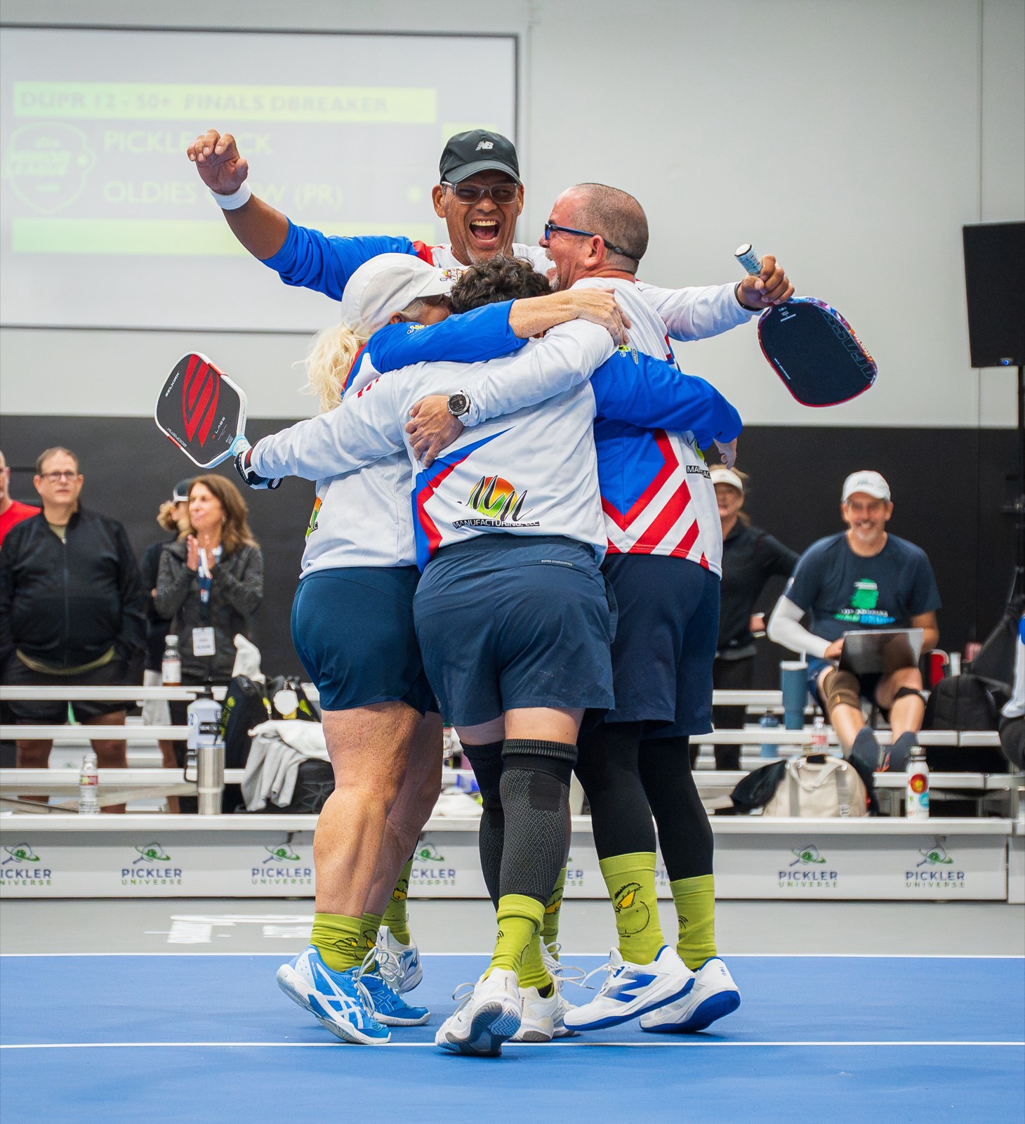 Teammates in national team jerseys celebrating in a huddle on court