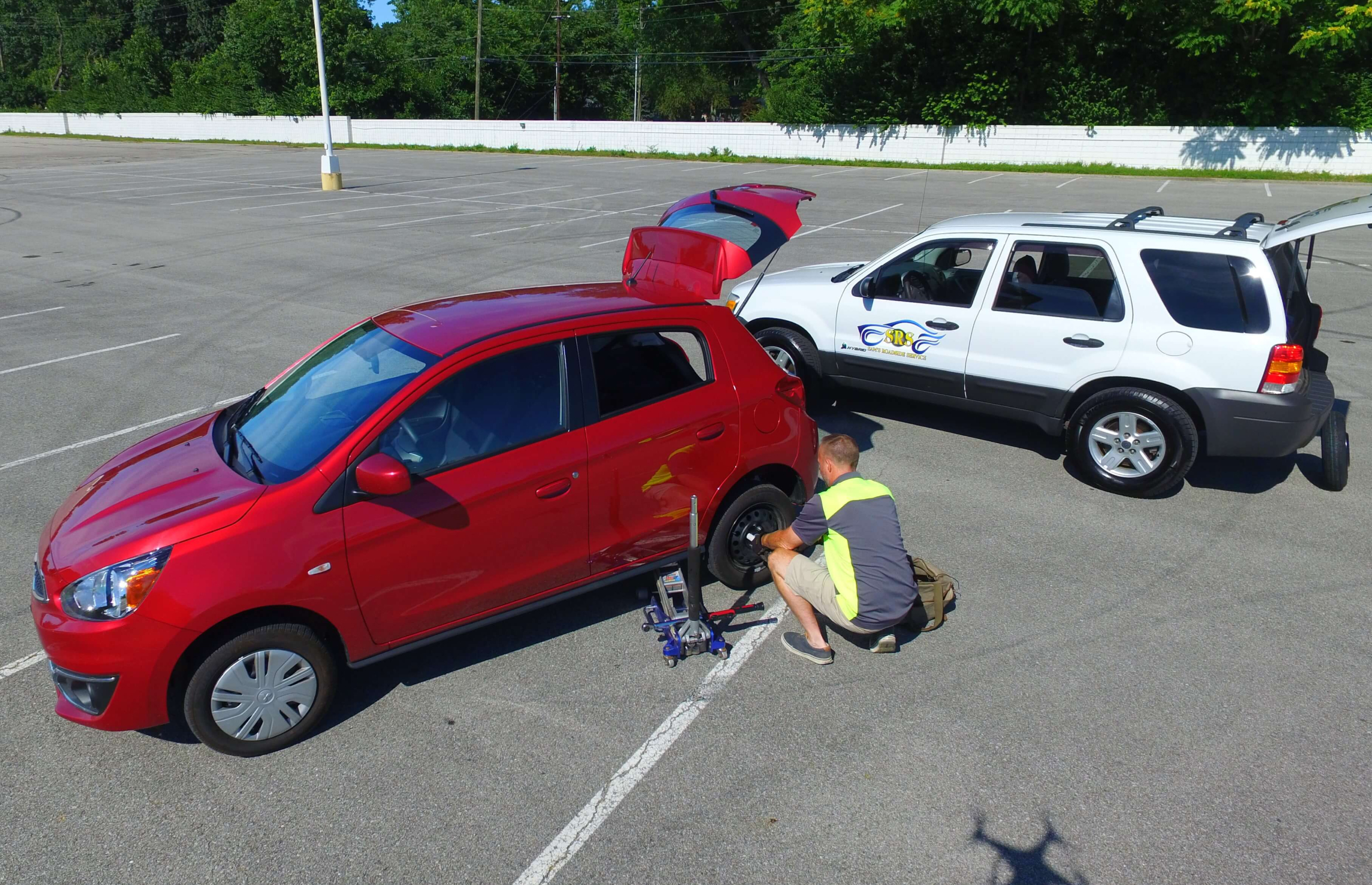 A Sam's Roadside Assistance technician lifting a car on jacks to patch a tire for them.