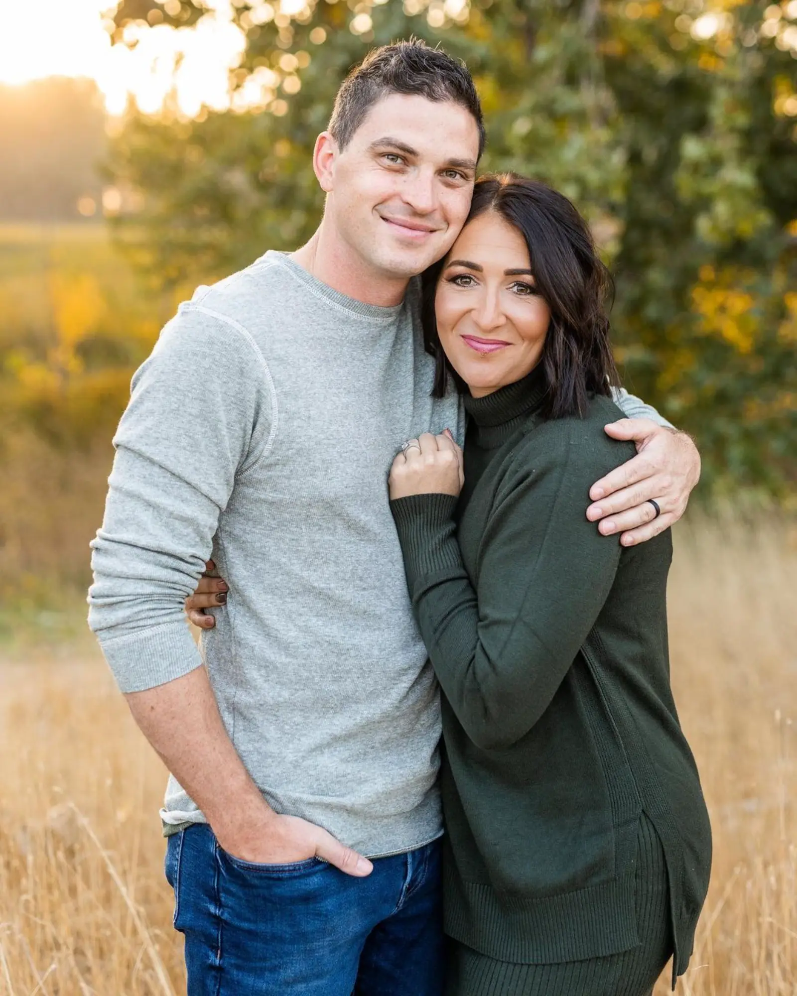 A couple smiling and embracing in a field. 