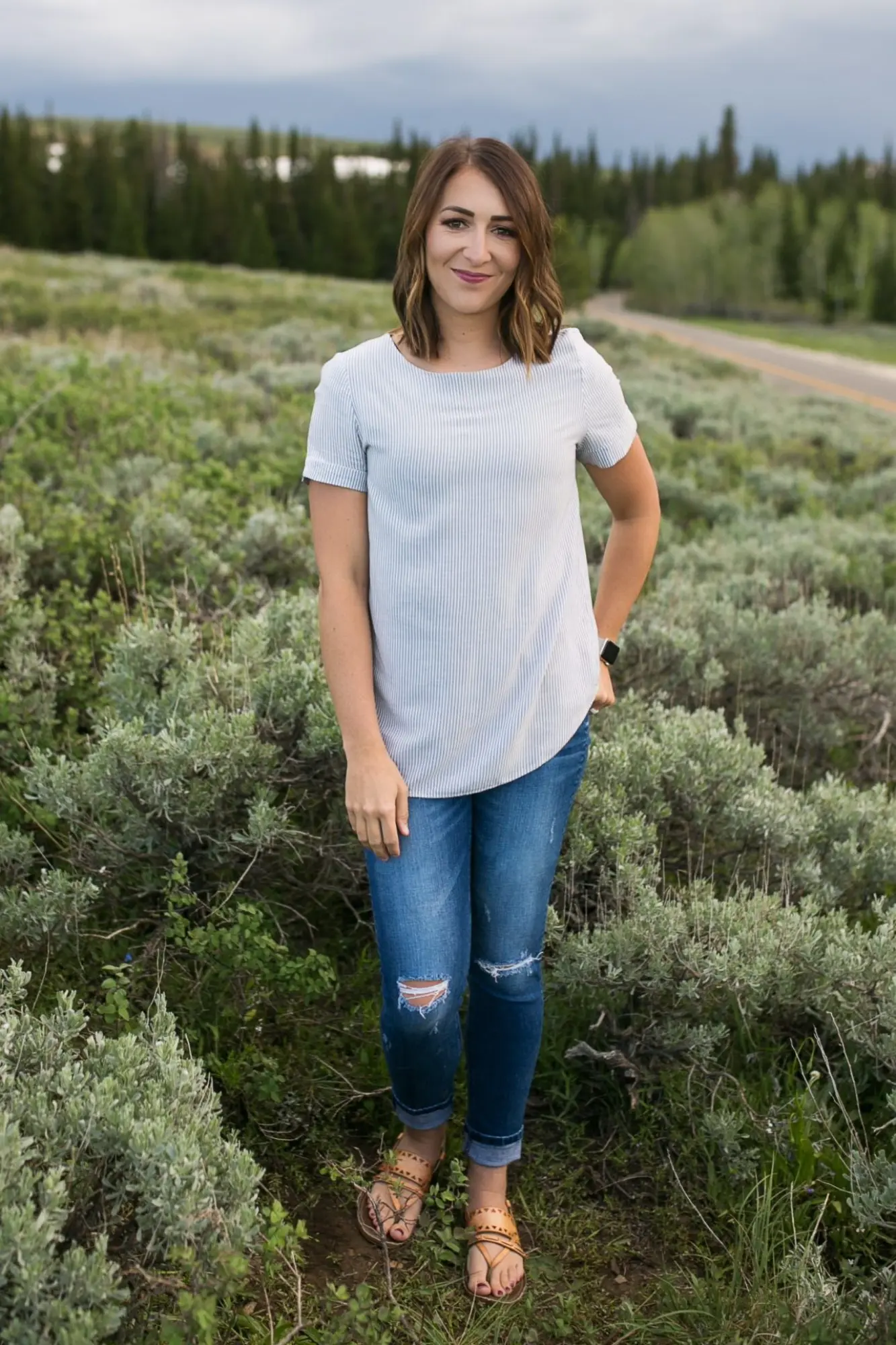 A woman in jeans and a t - shirt standing in a field.