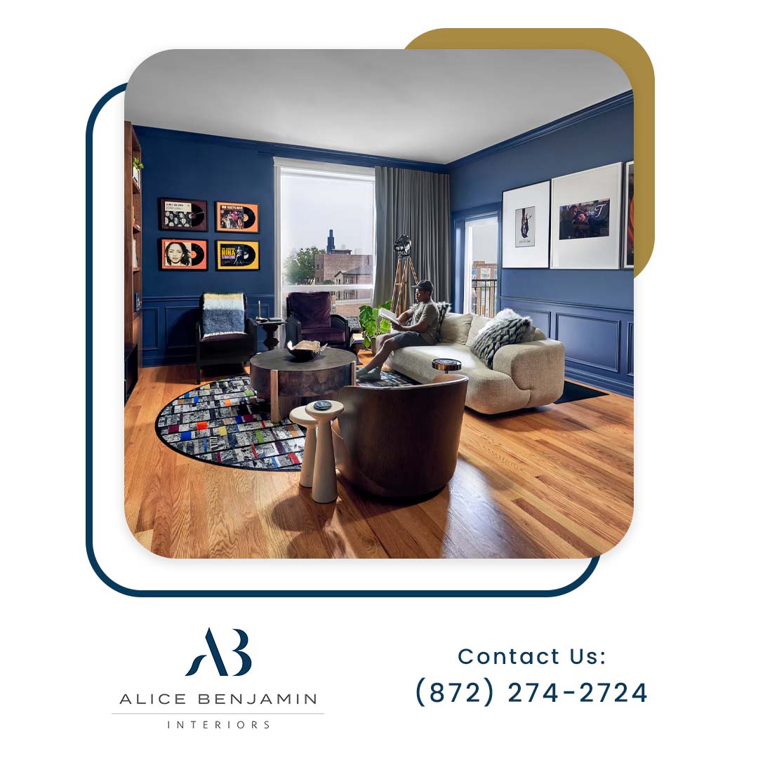 A person relaxing on a beige sofa in a modern living room featuring deep blue walls, hardwood floors, framed album art, and stylish contemporary furniture.