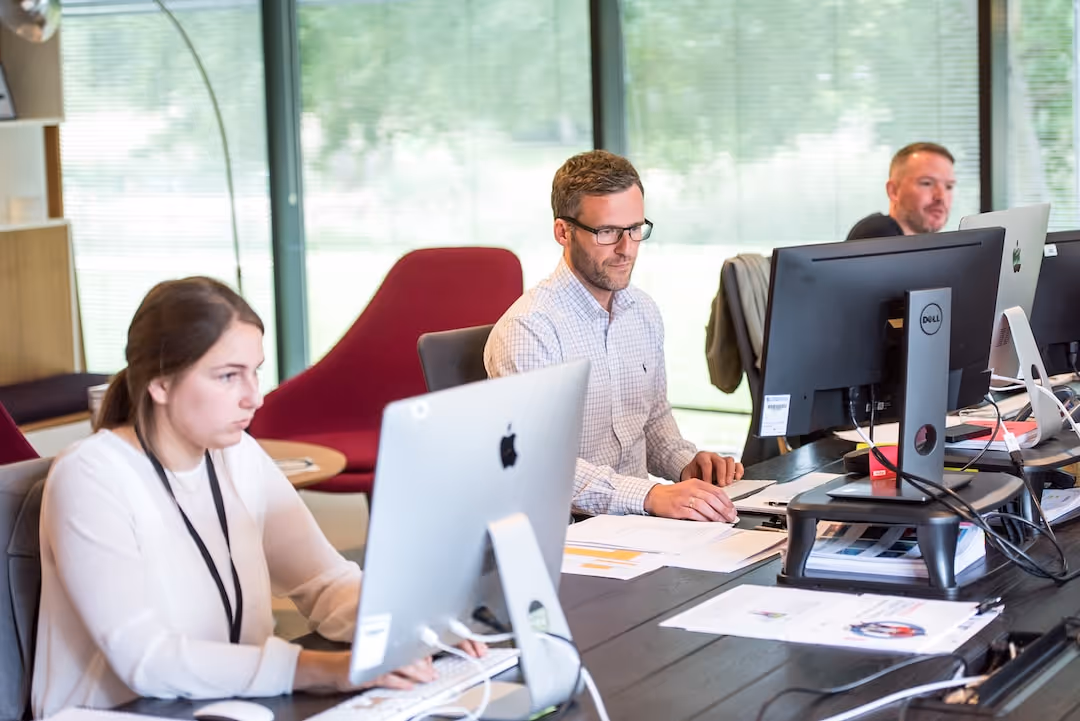 image of people at desk in front of computers