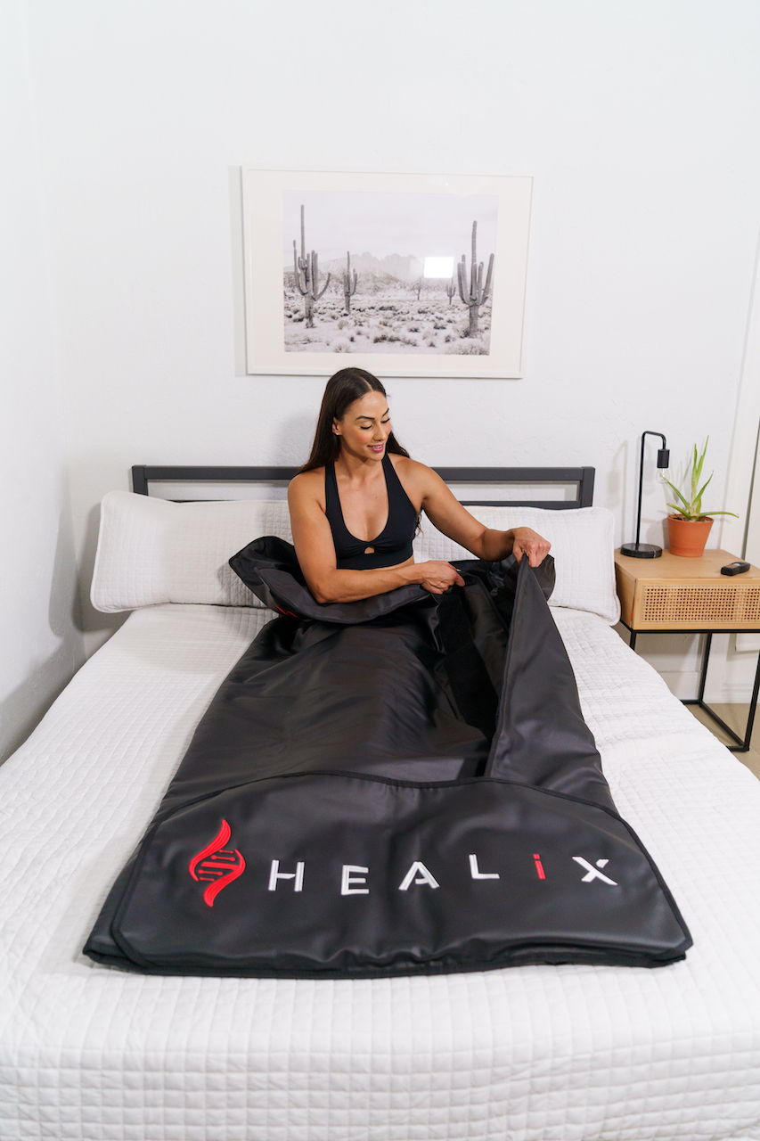 Woman in bed in a sauna infrared blanket with logo "HEALiX"