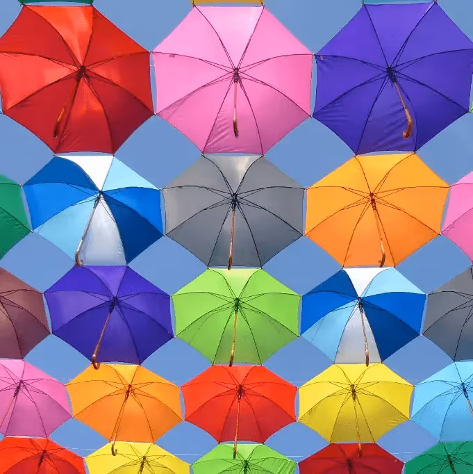 Brightly colored umbrellas suspended in a geometric pattern against the sky, symbolizing vibrant color use in email design.