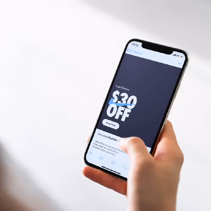 Person holding smartphone displaying promotional email with “\$30 OFF” discount offer, illustrating benefits of simple email templates.