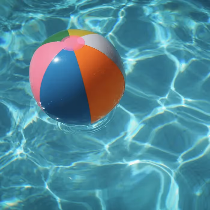 Colorful beach ball floating in a bright blue swimming pool, symbolizing fun, vibrant, and refreshing summer email design themes.