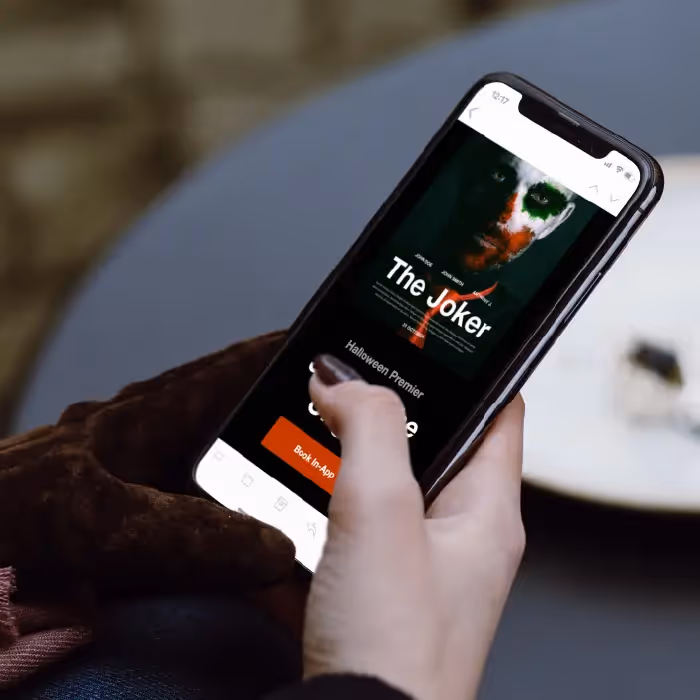 Person holding phone showing a Joker movie Halloween premiere email with a book ticket CTA.
