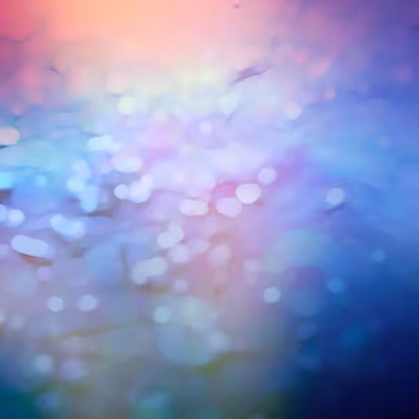 Pastel water bokeh: Abstract bokeh over shimmering water: soft-focus blue, purple, and pink light reflections dancing on a blurred surface